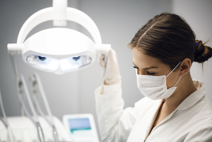 Female dentist adjusting illuminated lamp
